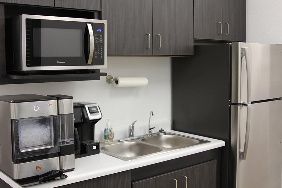 Recorrido por la oficina: área de cocina con microondas, cafetera, refrigerador y máquina de hielo