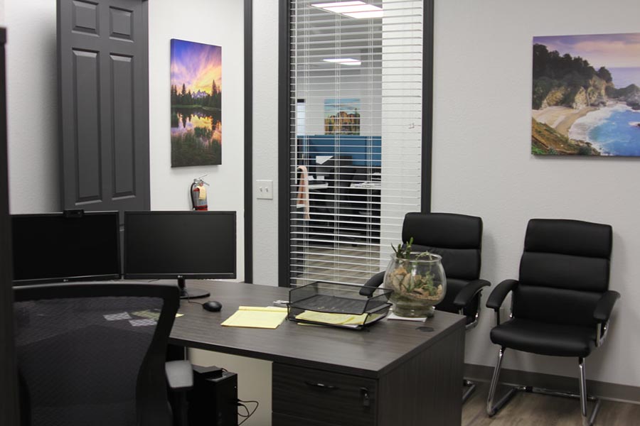 Recorrido por la oficina: interior de la oficina con dos monitores y papeleo en el escritorio, sillas negras y obras de arte del suroeste