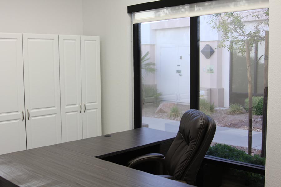 Recorrido por la oficina: área de recepción con escritorio grande, silla y ventana grande con vista al área ajardinada