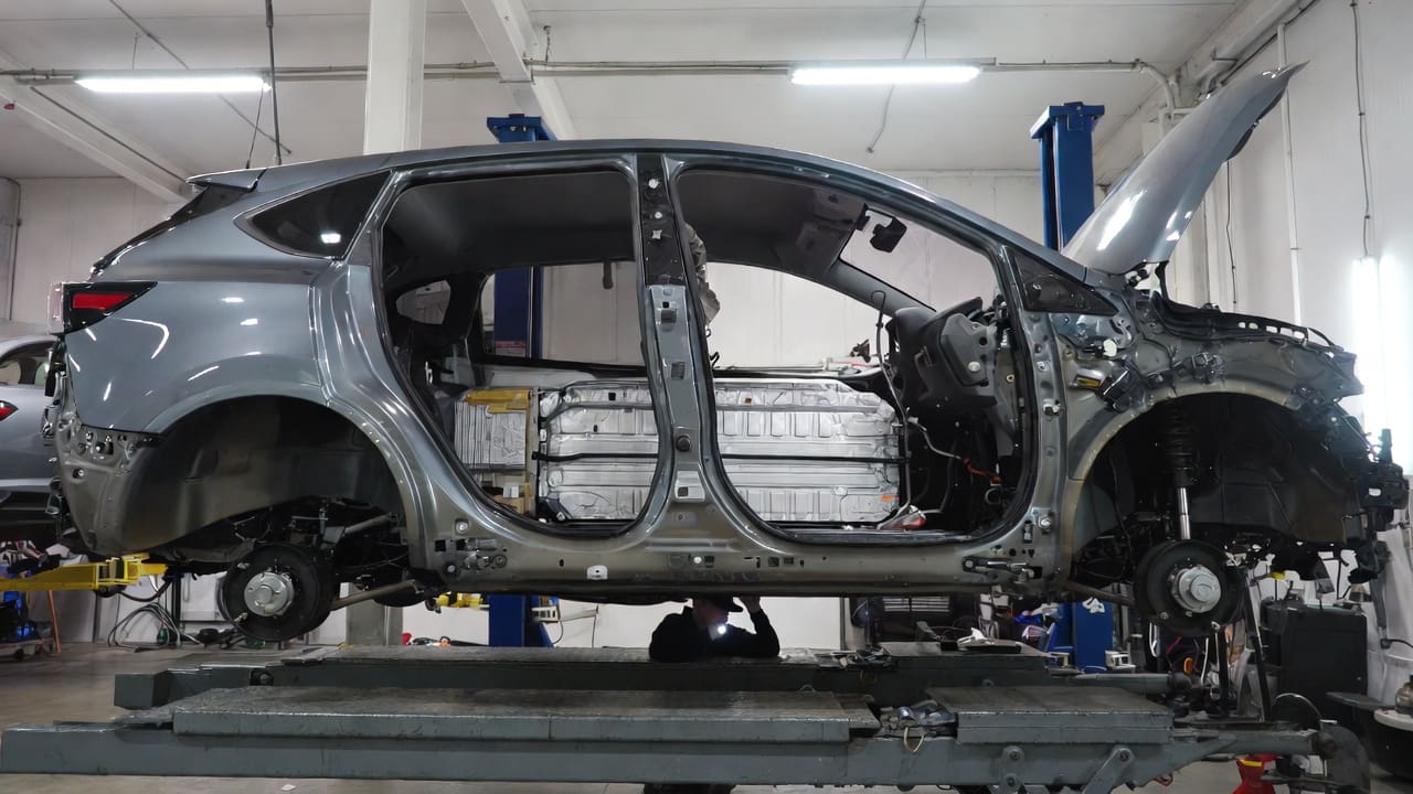 Vehículo híbrido en un elevador con la batería expuesta durante la inspección de daños del seguro